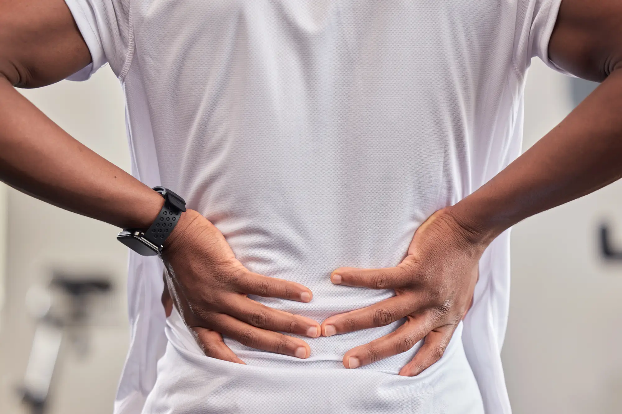 Person pressing both hands to their lower back in pain