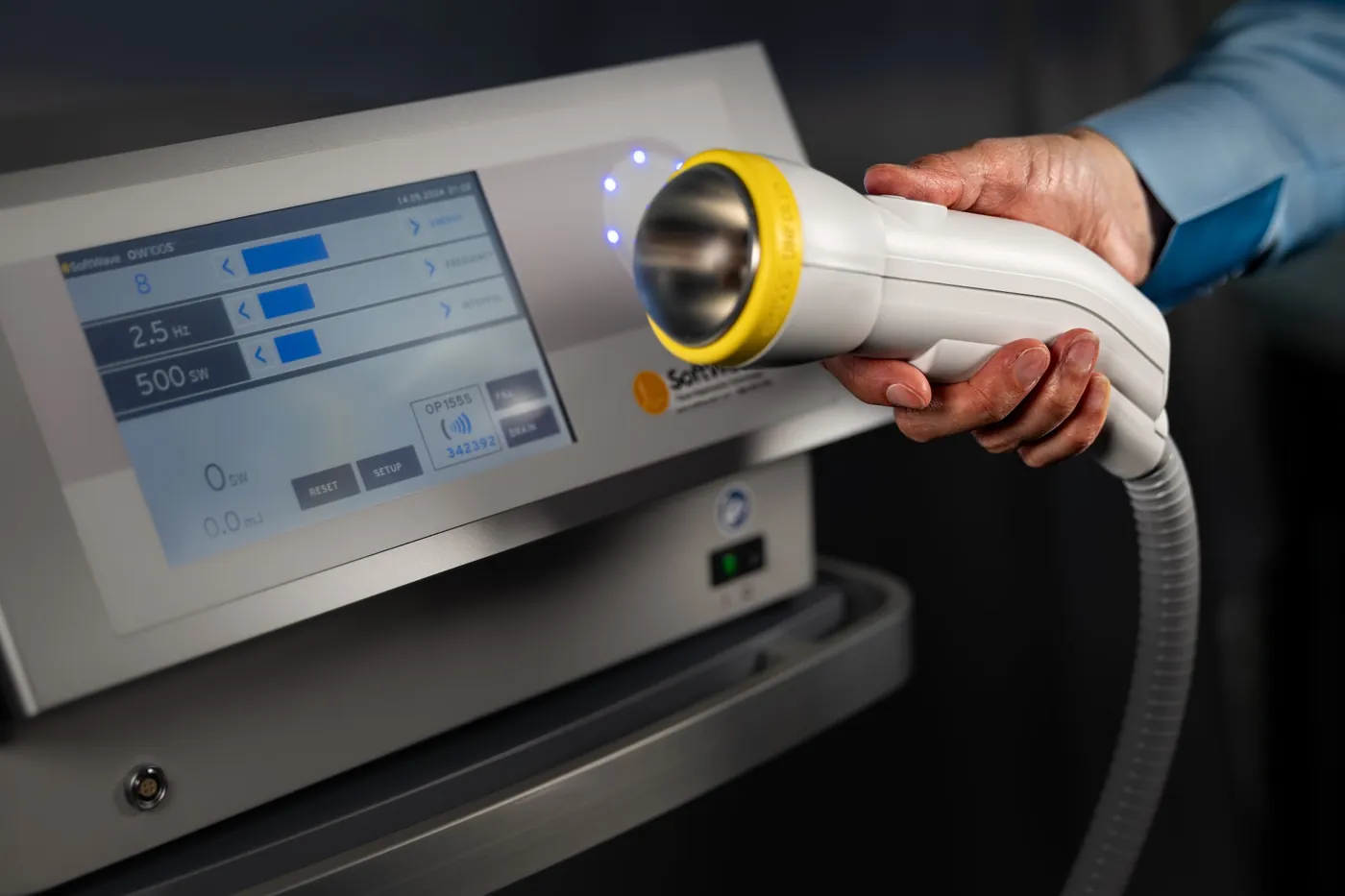 Clinician holding the SoftWave applicator in front of the SoftWave device