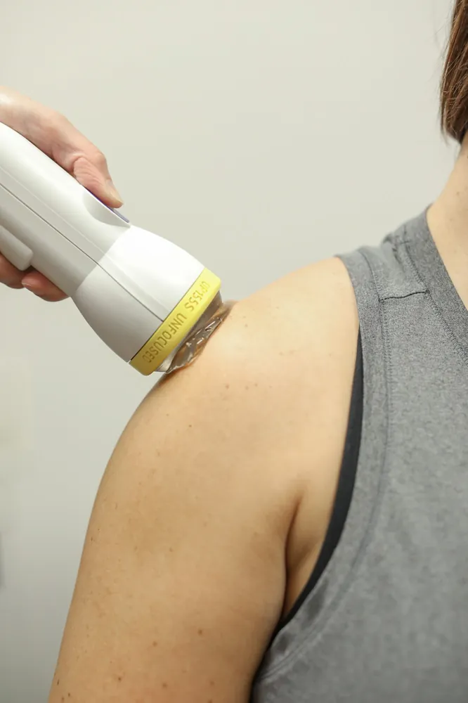Clinician treating a patient's shoulder with the SoftWave applicator