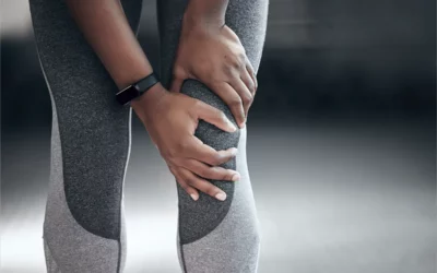 Person in athletic wear holding knee, indicating pain, relevant to physical therapy and rehabilitation topics.